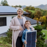 Femme enceinte avec petit garçon tenant des panneaux solaires devant leur maison